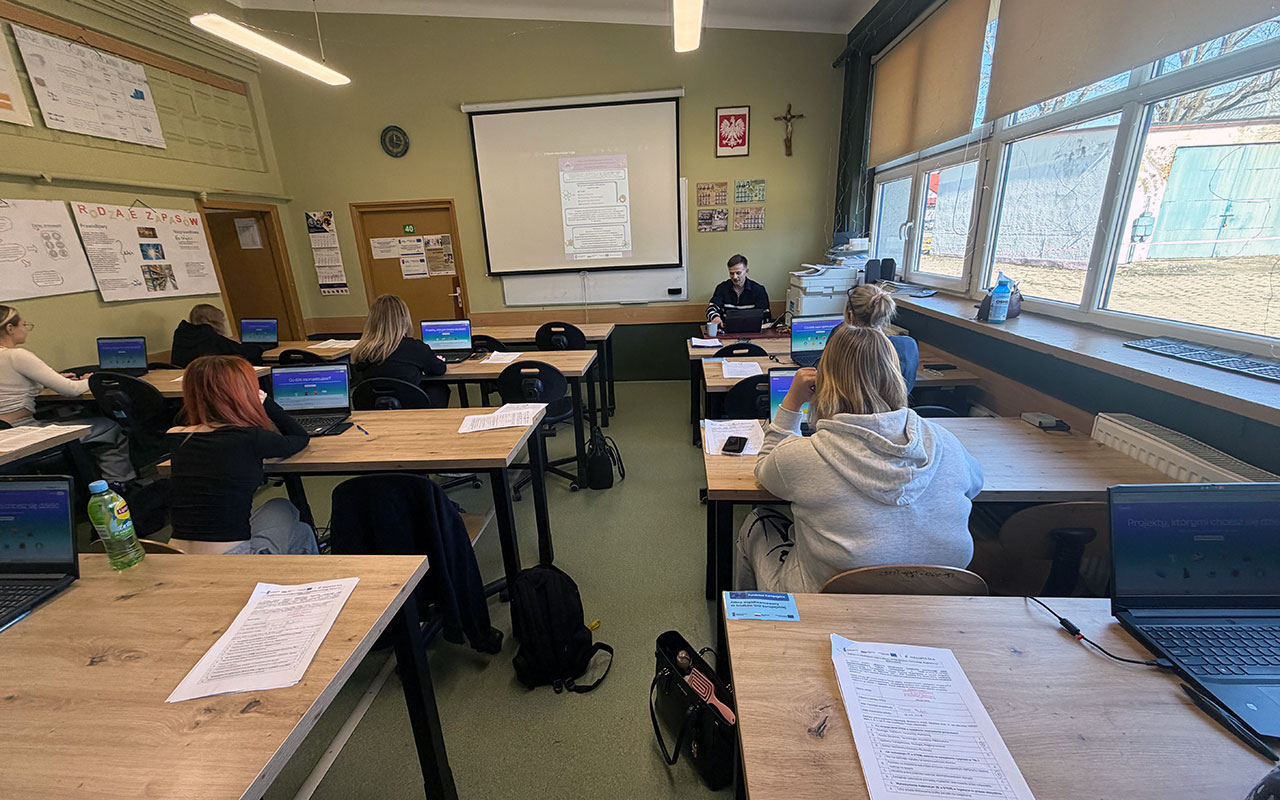 Zajecia w klasie kilku yuczniow przy laptopach z przodu
