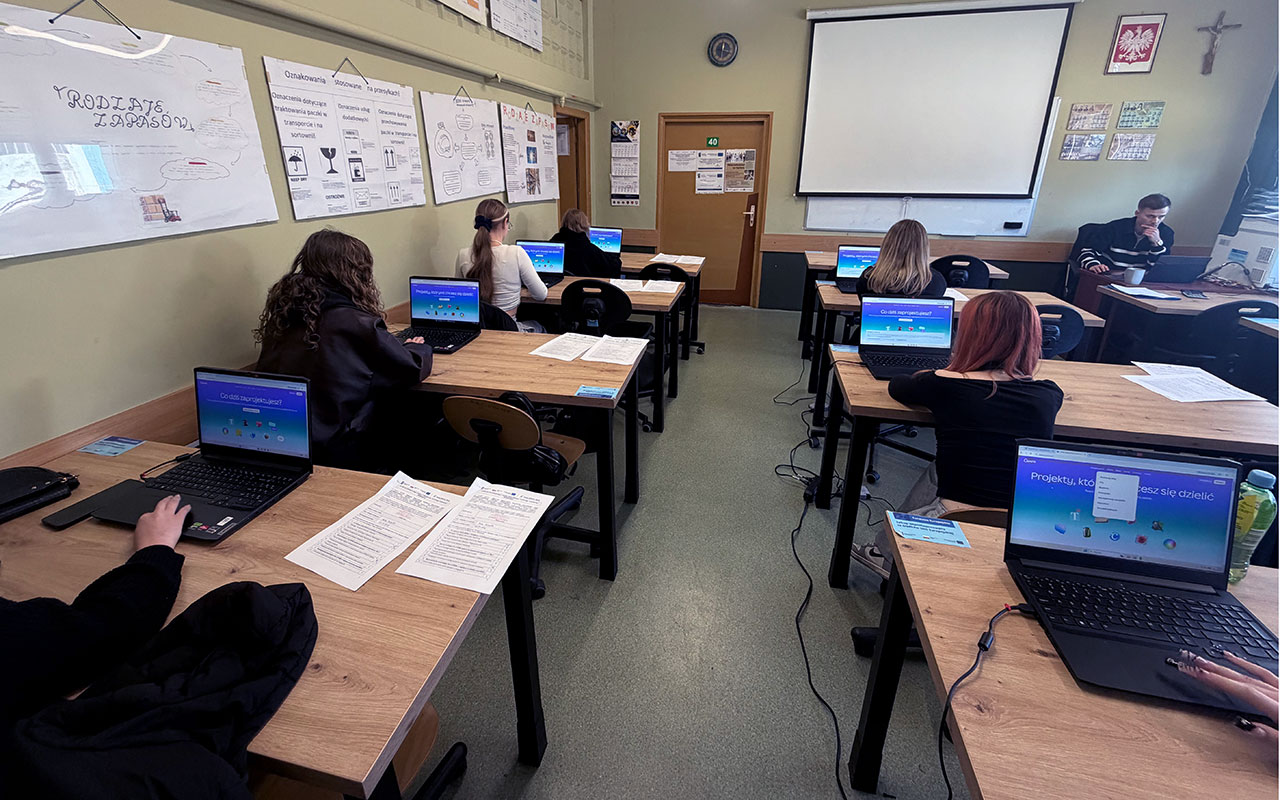 Zajecia w klasie kilku yuczniow przy laptopach z tylu