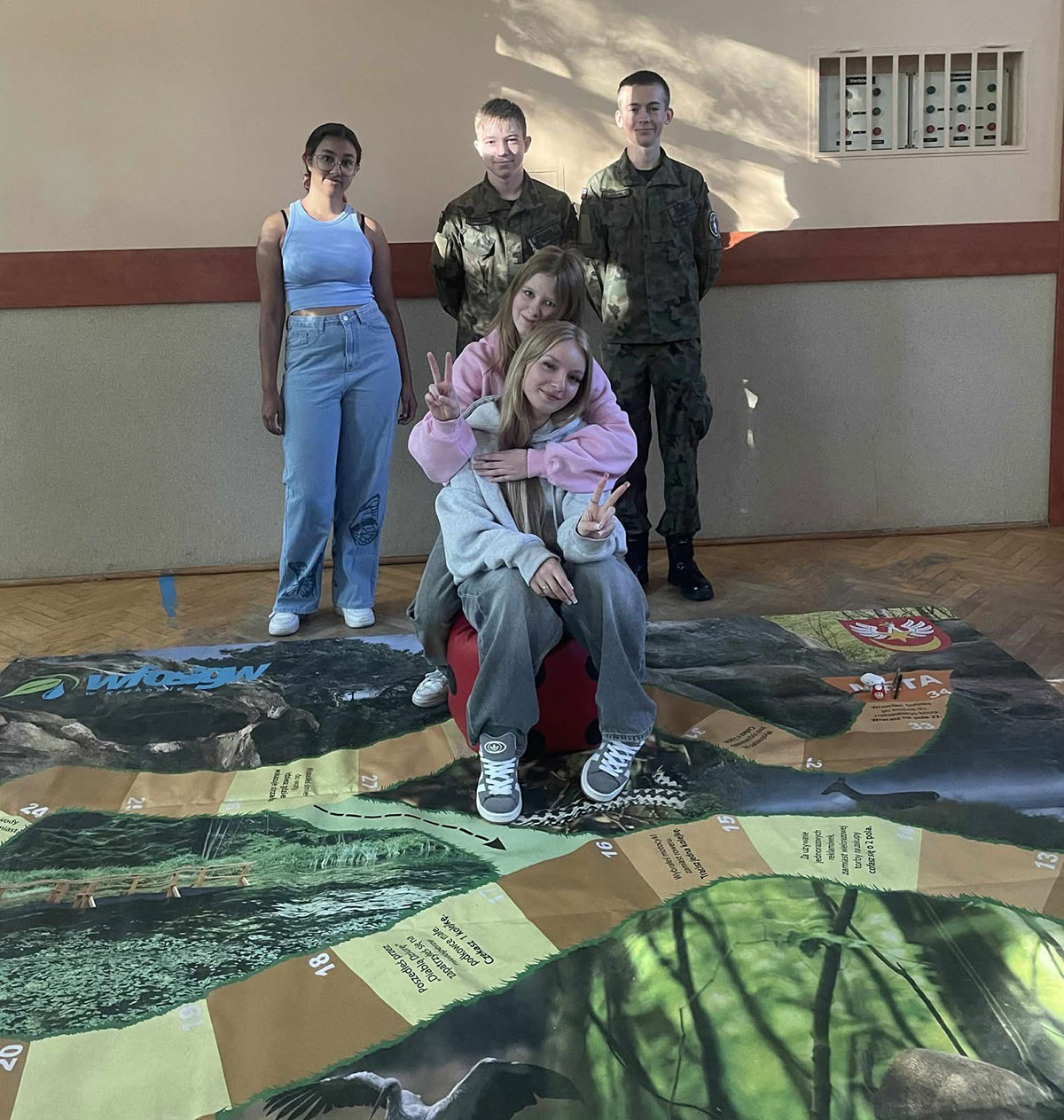 Uczniowie rzucający kostką podczas konkursu gry wielkoformatowej.