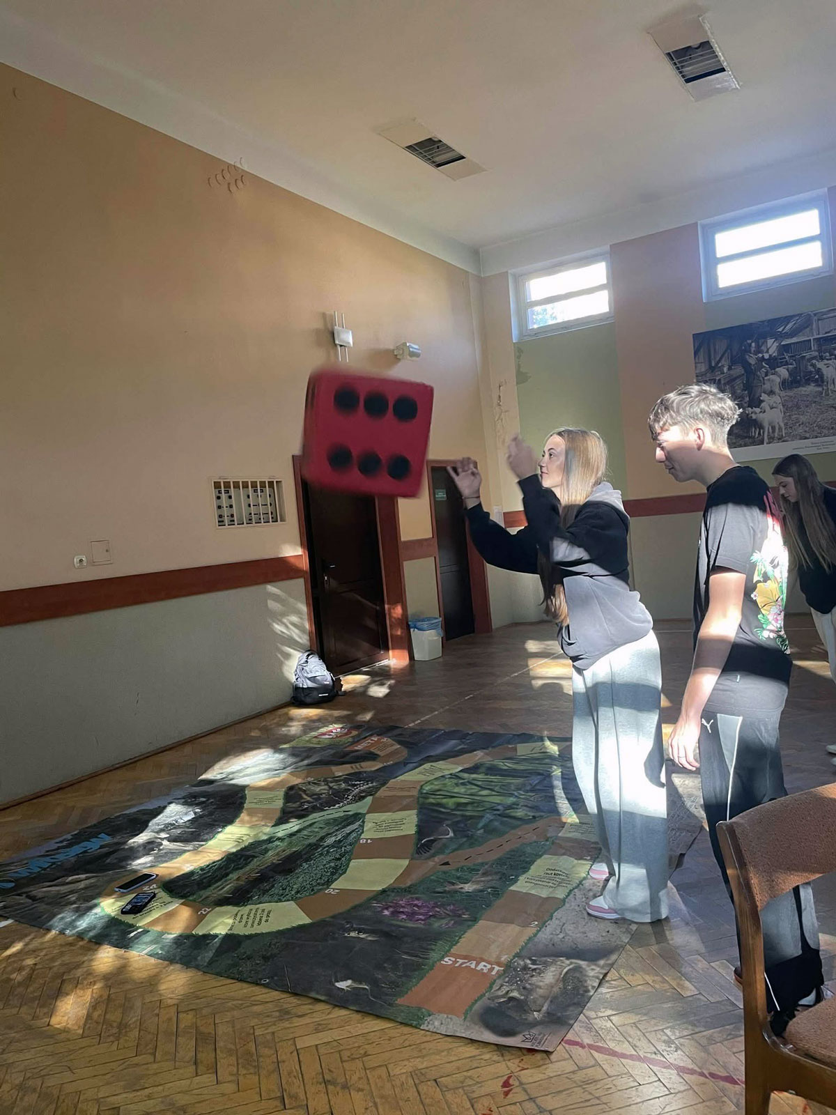 Uczniowie rzucający kostką podczas konkursu gry wielkoformatowej.